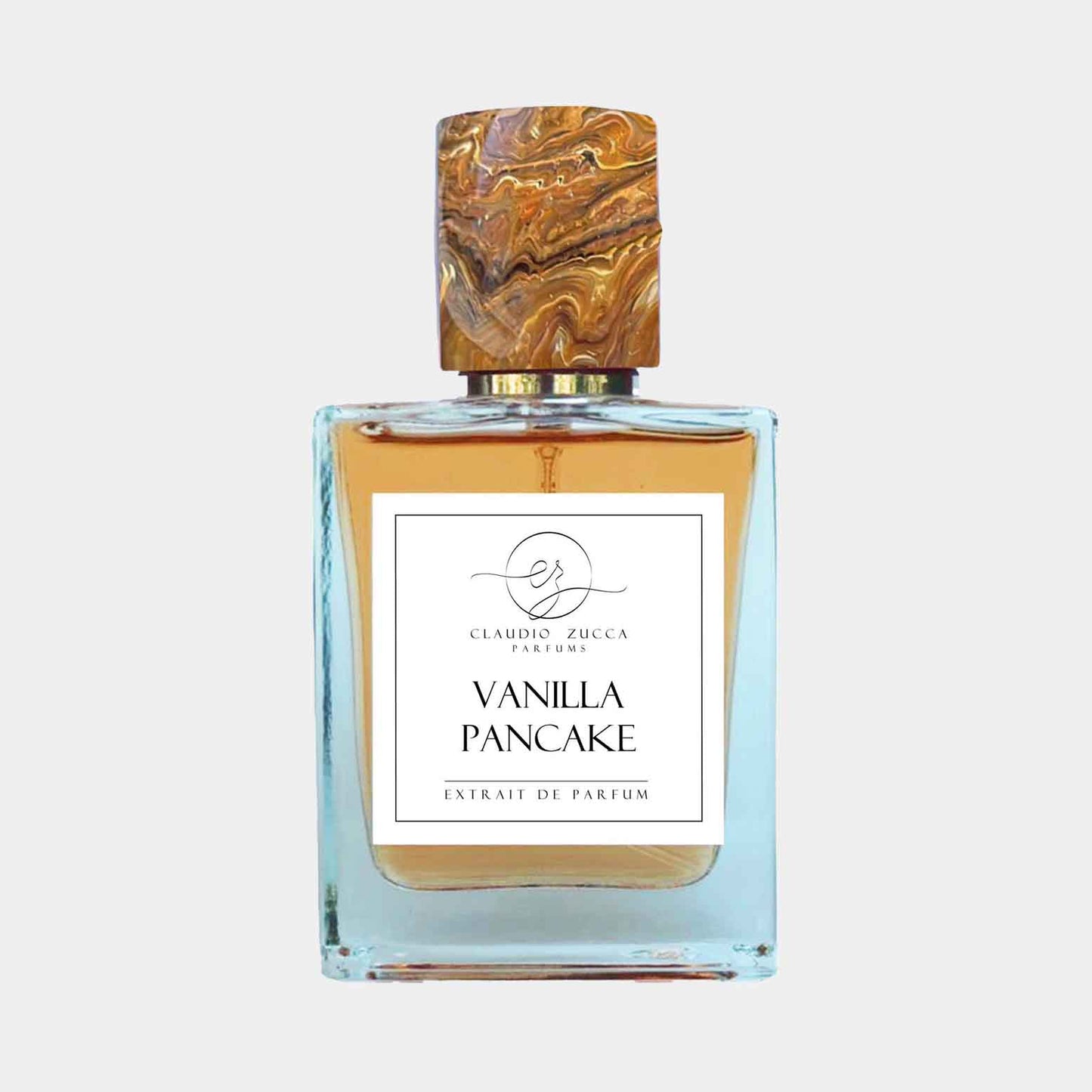 Fles parfum van Claudio Zucca met de naam Vanilla Pancake erop, met een stijlvolle, marmeren dop en een helder vloeistof in een elegante fles.
