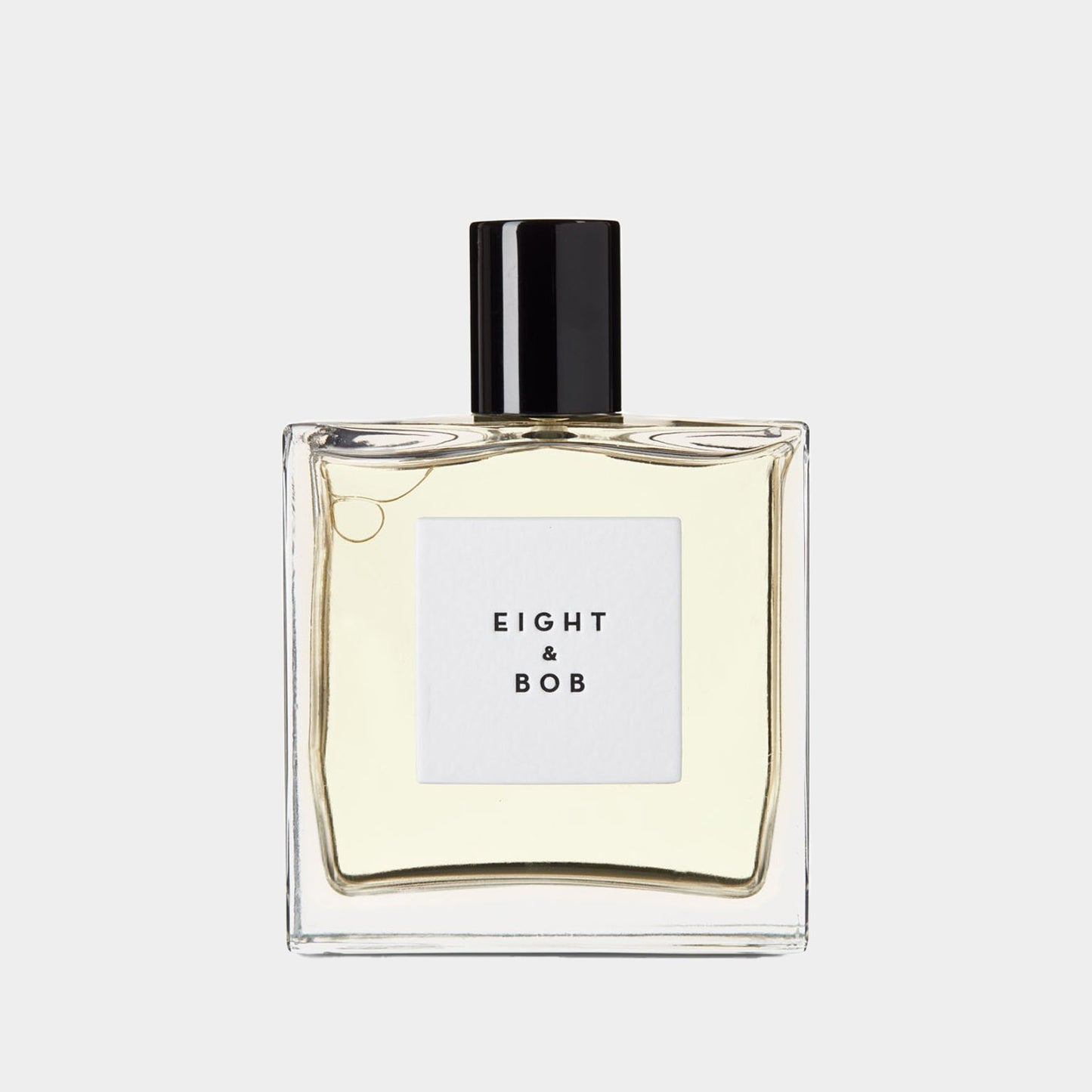 Een flesje parfum van Eight and Bob The Original, met een strakke, minimalistische uitstraling en een zwarte dop. Het parfum heeft een lichtgele kleur en zit in een vierkante flacon.