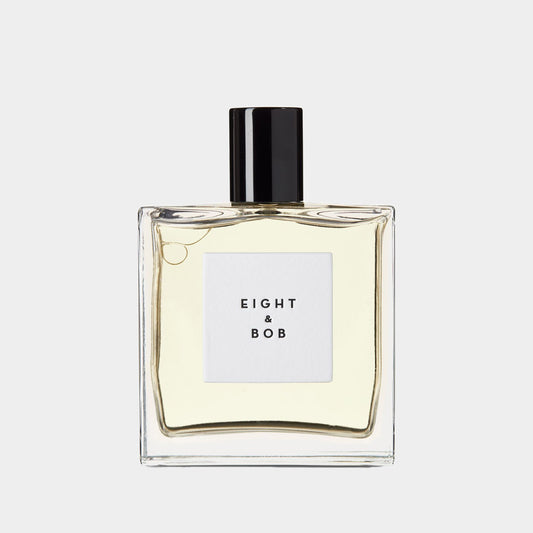 Een flesje parfum van Eight and Bob The Original, met een strakke, minimalistische uitstraling en een zwarte dop. Het parfum heeft een lichtgele kleur en zit in een vierkante flacon.