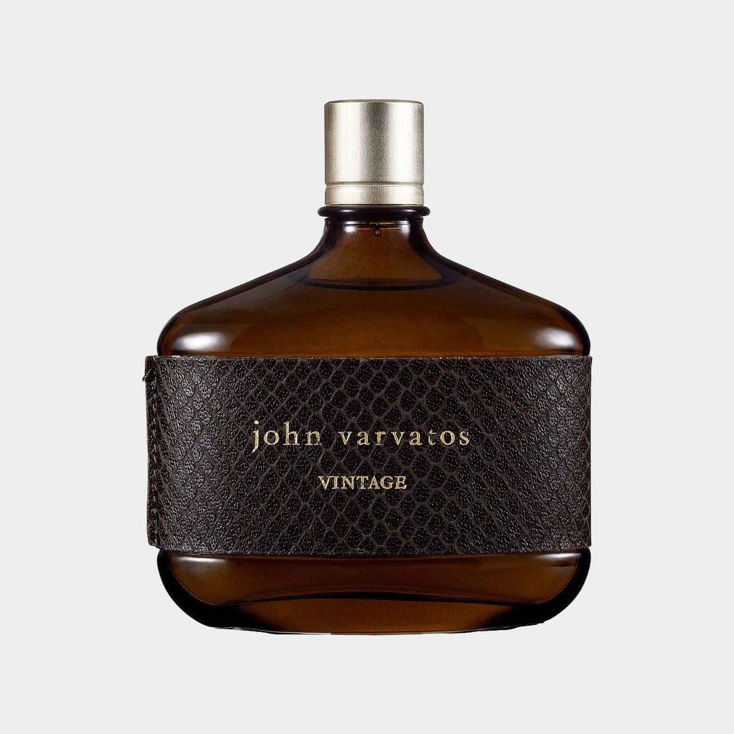 Een bruine glazen flacon met een leren label en john varvatos VINTAGE erop gedrukt, die het geurmonster van John Varvatos Vintage vertegenwoordigt. De flacon heeft een elegante, tijdloze uitstraling.