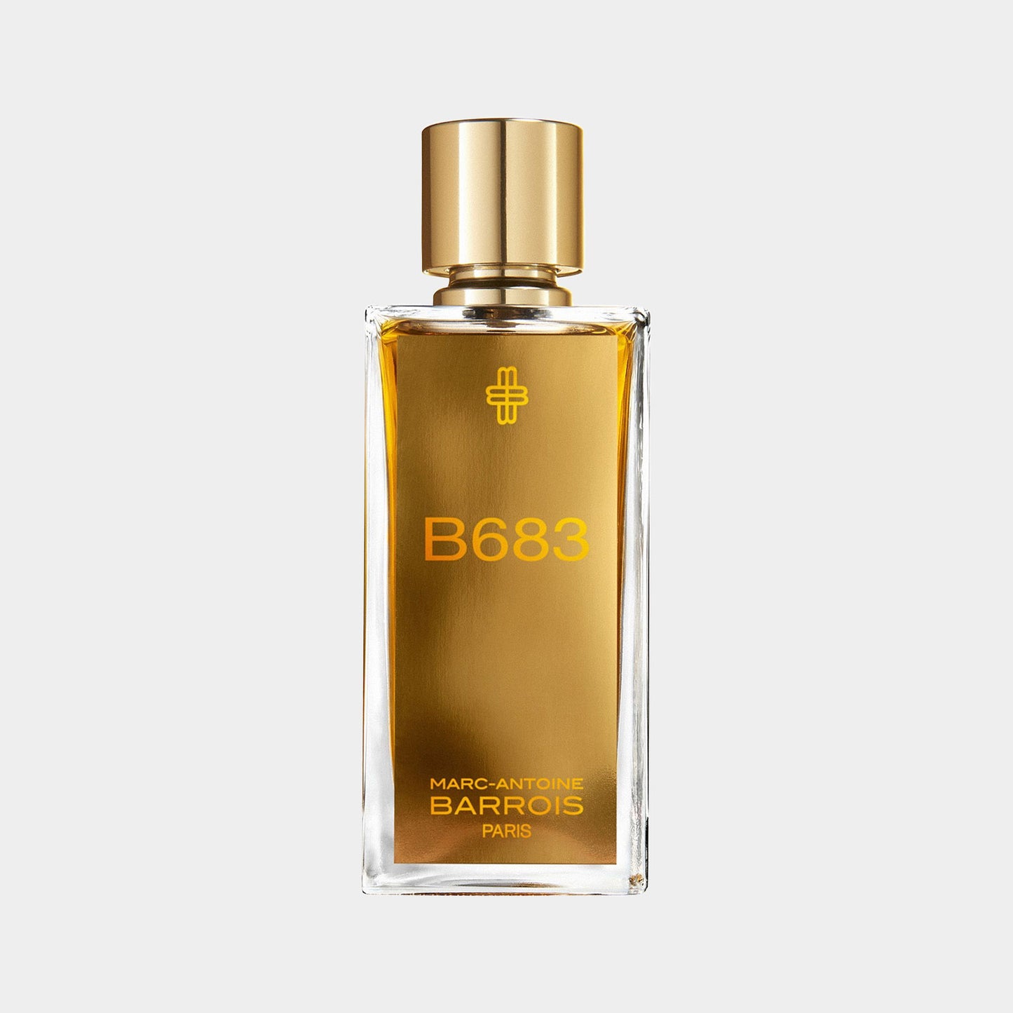 Fles van de parfum B683 van Marc-Antoine Barrois, met een elegante gouden dop en een amberkleurige vloeistof, gepresenteerd op een lichte achtergrond.