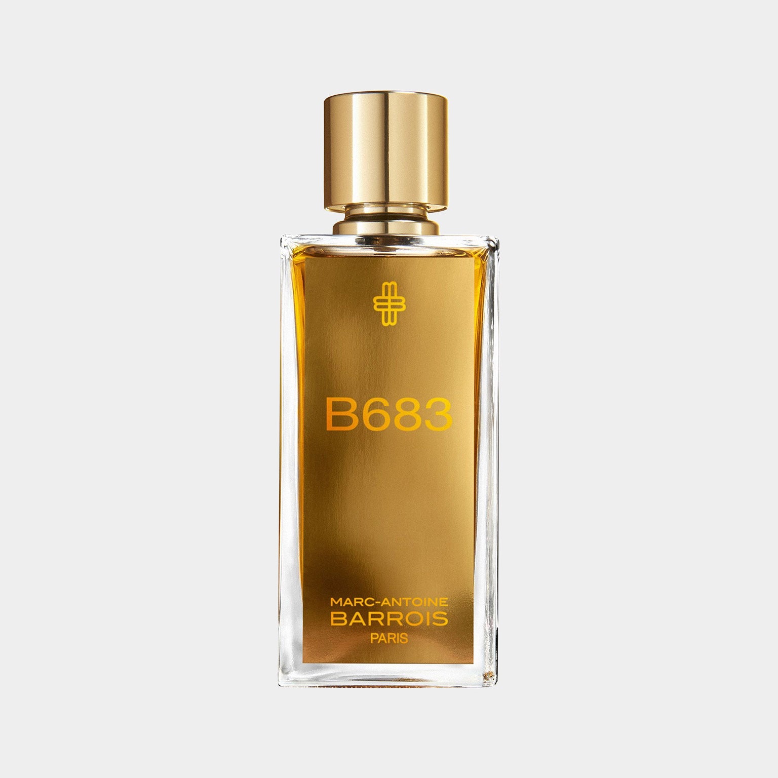 Fles van de parfum B683 van Marc-Antoine Barrois, met een elegante gouden dop en een amberkleurige vloeistof, gepresenteerd op een lichte achtergrond.