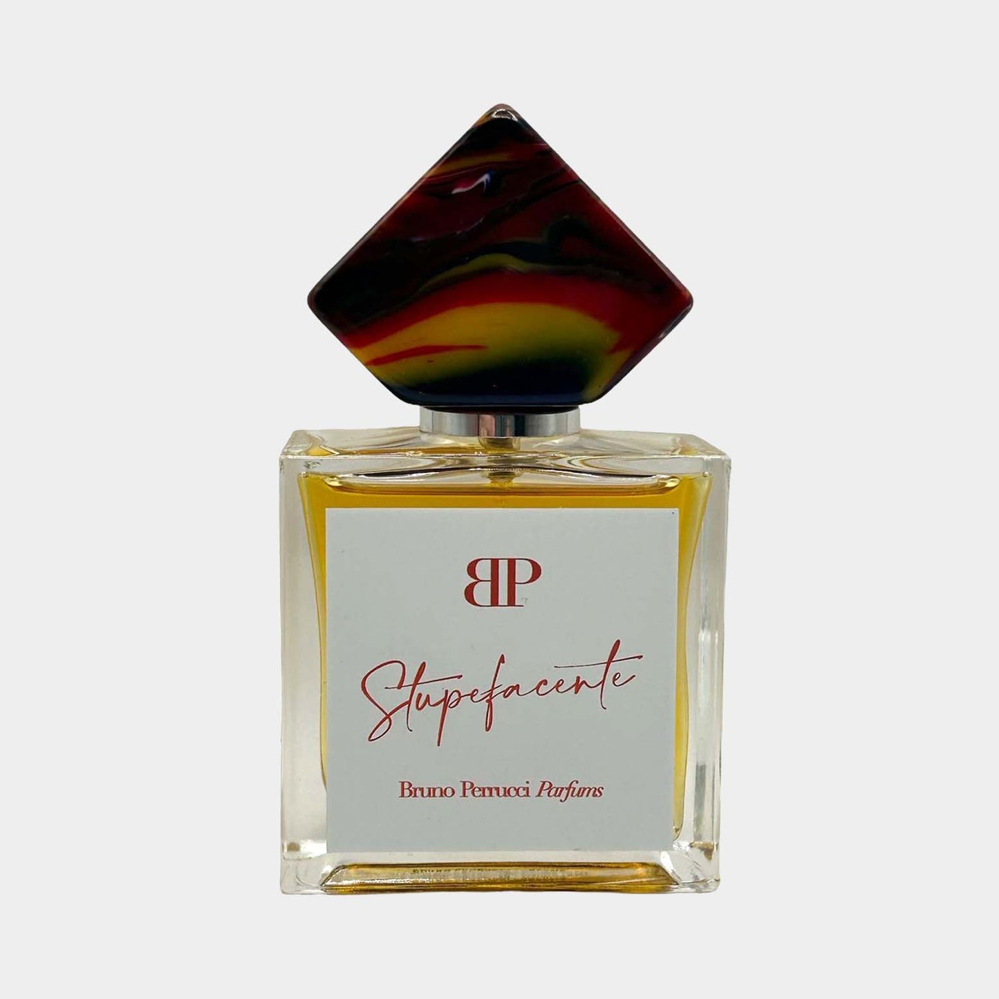 Een afbeelding van het parfum Stupefacente Sample van Bruno Perrucci, gepresenteerd in een elegante glazen fles met een opvallende, kleurrijke dop.