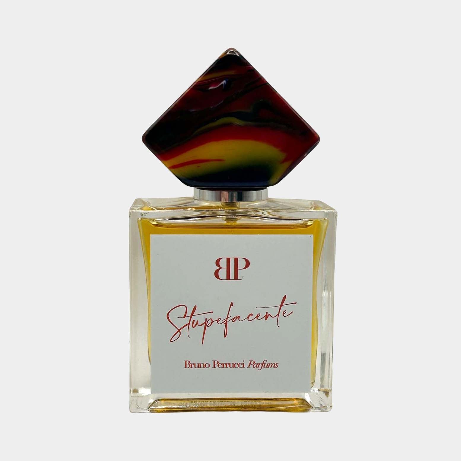 Een afbeelding van het parfum Stupefacente Sample van Bruno Perrucci, gepresenteerd in een elegante glazen fles met een opvallende, kleurrijke dop.