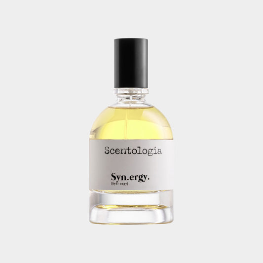 Een flesje van 30 ml Scentologia Syn.ergy Sample, gevuld met een lichtgele geur, met een zwarte dop en een minimalistisch etiket.