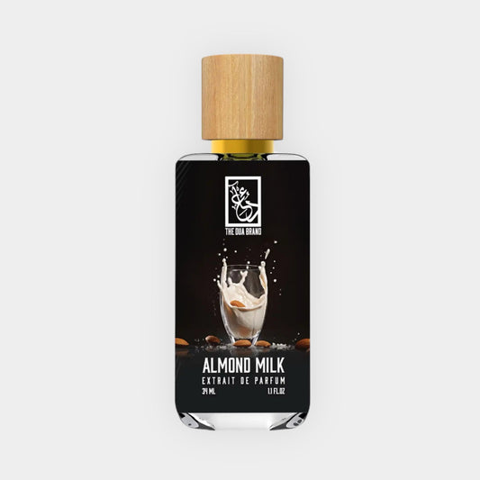 Monsterfles van Dua Almond Milk, met een elegante zwarte verpakking en een houten dop. De inhoud toont een spetter van amandelmelk.