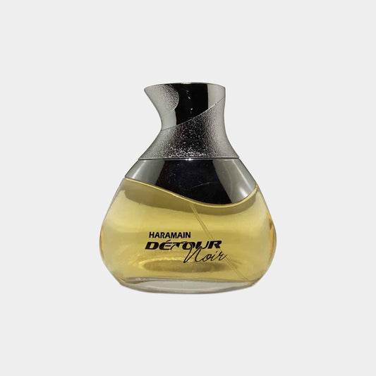 Al Haramain Détour Noir Sample is a stylish, curved glass fragrance bottle showcasing a warm, amber liquid. The sleek design is accentuated by a metallic silver cap, reflecting elegance and sophistication.
