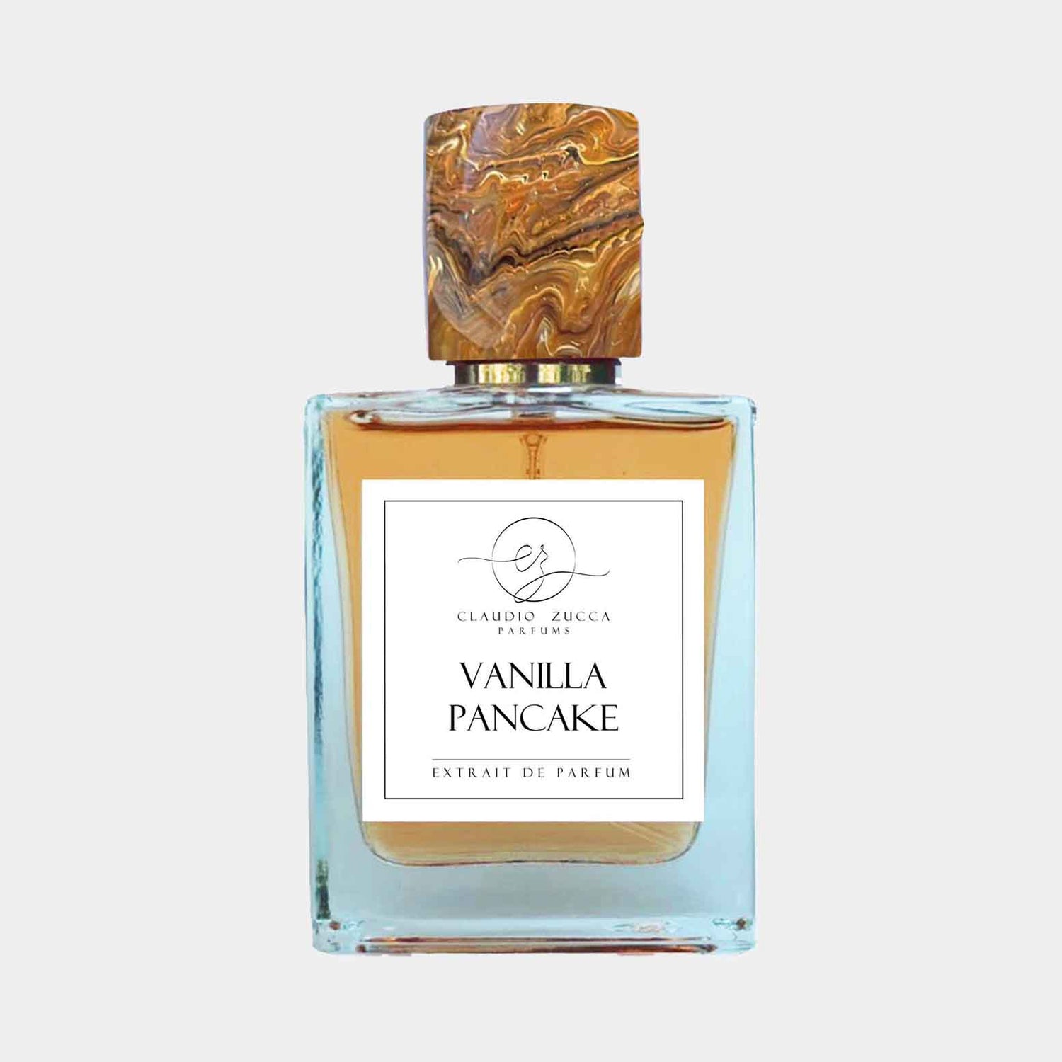 Fles parfum van Claudio Zucca met de naam Vanilla Pancake erop, met een stijlvolle, marmeren dop en een helder vloeistof in een elegante fles.